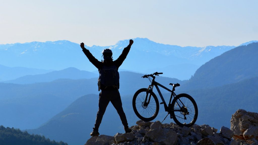 Ciclista esulta sulla cima di un monte