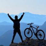 Ciclista esulta sulla cima di un monte