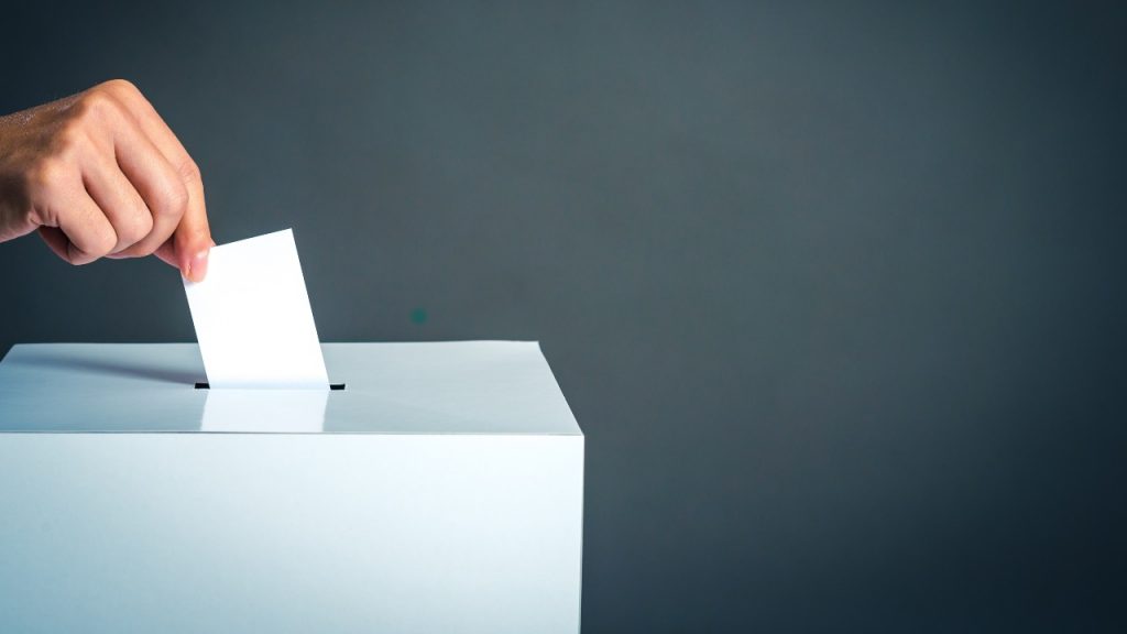 Mano depone una scheda in un'urna elettorale